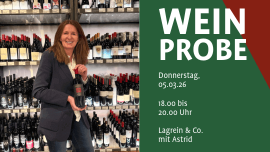 Person in dunklem Blazer hält eine Weinflasche vor einem Regal mit vielen Weinflaschen